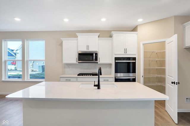 kitchen featuring white cabinetry, appliances with stainless steel finishes, plenty of natural light, and a center island with sink