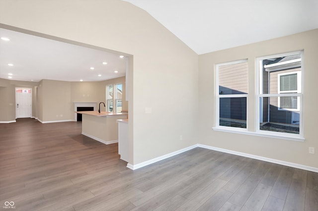 unfurnished room with sink, vaulted ceiling, and light hardwood / wood-style flooring