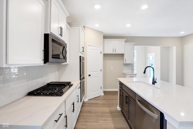 kitchen featuring sink, a center island with sink, white cabinets, and appliances with stainless steel finishes