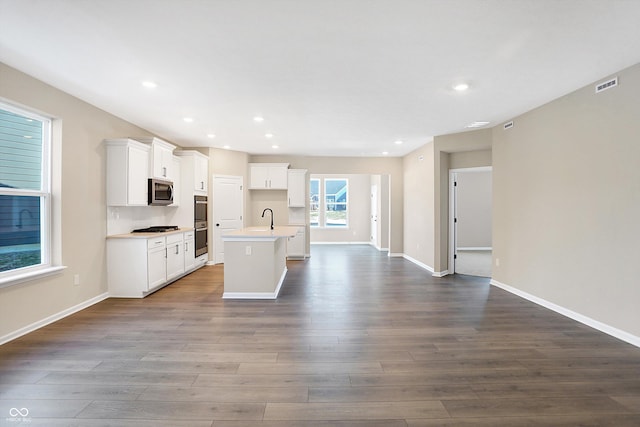 kitchen featuring dark hardwood / wood-style flooring, gas cooktop, white cabinets, and a center island with sink