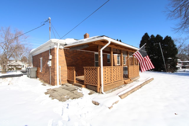 snow covered back of property with a porch