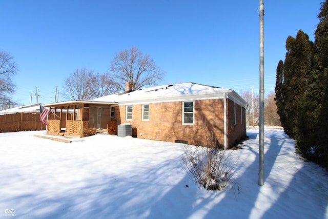 snow covered rear of property featuring cooling unit