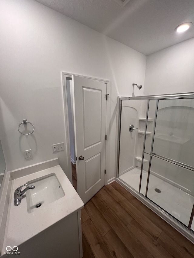 bathroom featuring hardwood / wood-style flooring, vanity, and walk in shower