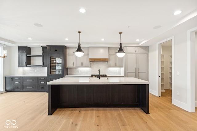 kitchen featuring decorative backsplash, gray cabinets, decorative light fixtures, light hardwood / wood-style floors, and custom range hood