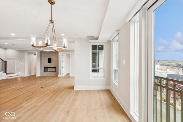 unfurnished living room featuring a fireplace, light hardwood / wood-style floors, and a notable chandelier