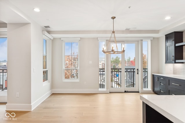 unfurnished dining area with a notable chandelier and light wood-type flooring