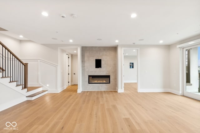 unfurnished living room featuring a tile fireplace and light hardwood / wood-style flooring