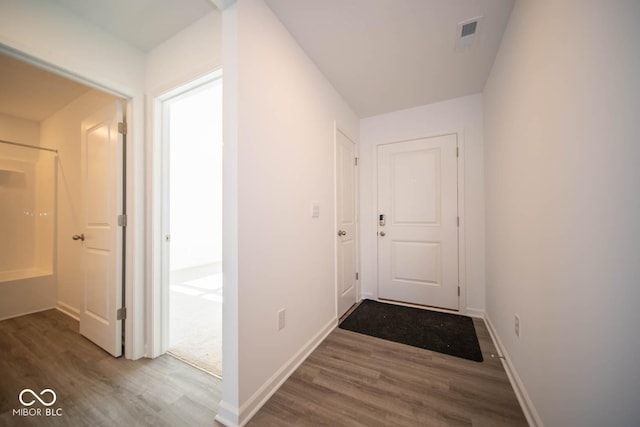 hall featuring baseboards, visible vents, and dark wood-type flooring