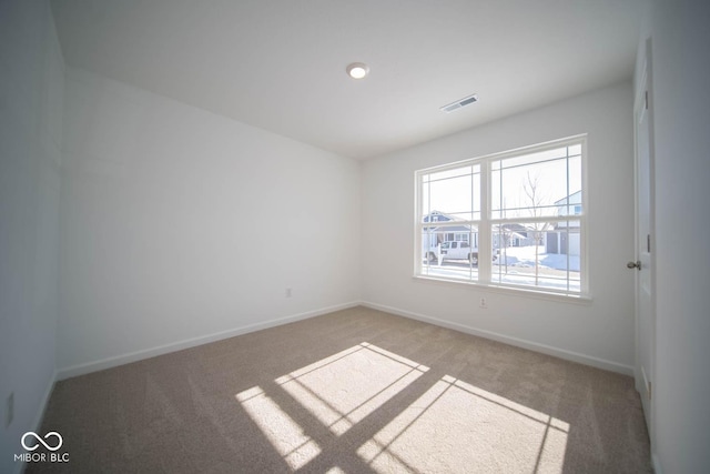 unfurnished room featuring light colored carpet, visible vents, and baseboards