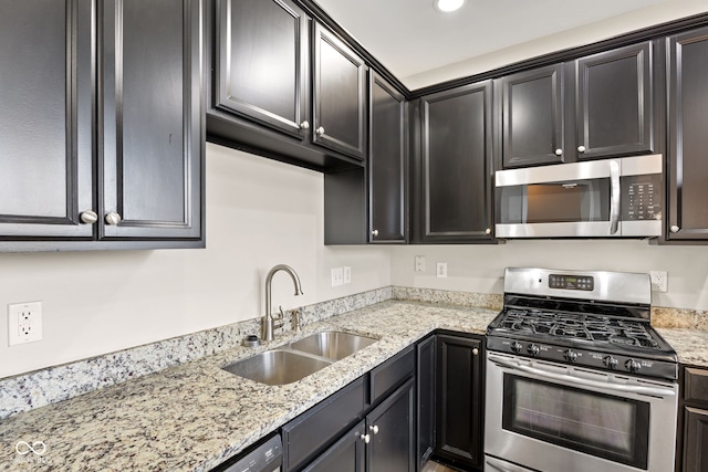 kitchen with stainless steel appliances, light stone counters, and sink