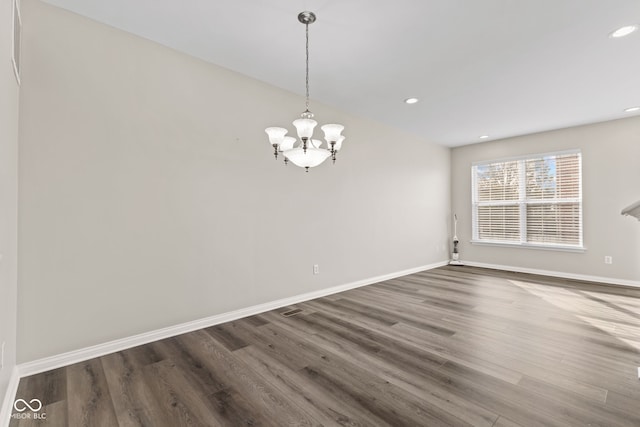 spare room featuring a chandelier and dark hardwood / wood-style flooring