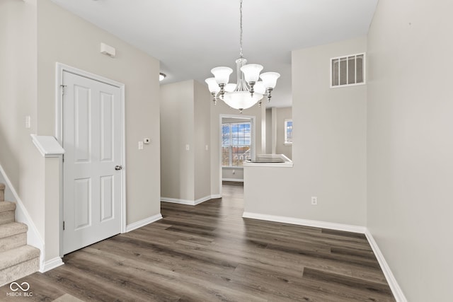 unfurnished dining area featuring dark hardwood / wood-style flooring and an inviting chandelier