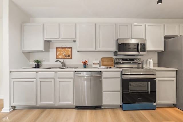 kitchen with appliances with stainless steel finishes, light wood-type flooring, white cabinetry, and sink