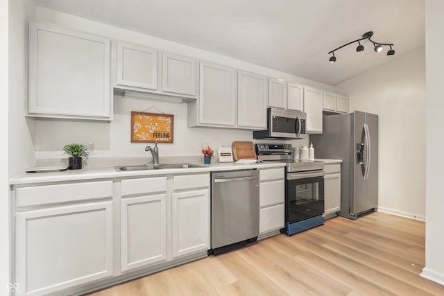 kitchen with white cabinetry, sink, rail lighting, stainless steel appliances, and light hardwood / wood-style flooring