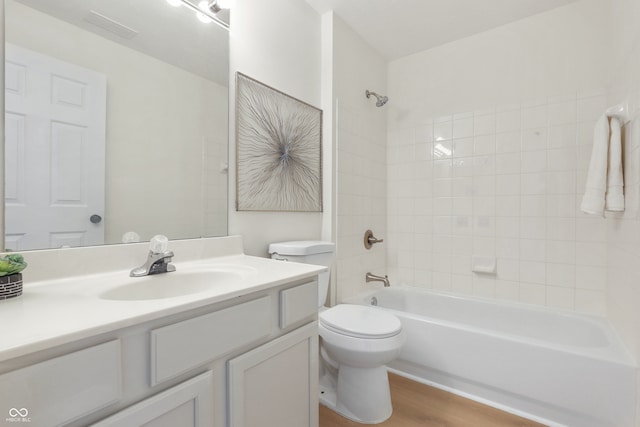 full bathroom with hardwood / wood-style floors, vanity, tiled shower / bath combo, and toilet