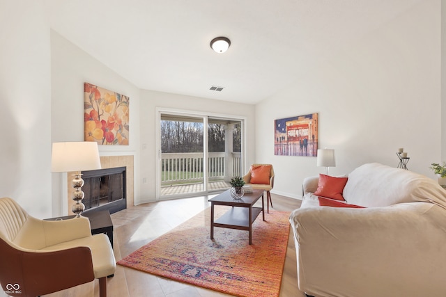 tiled living room with vaulted ceiling and a tiled fireplace