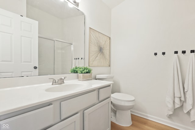 bathroom featuring toilet, vanity, wood-type flooring, and walk in shower