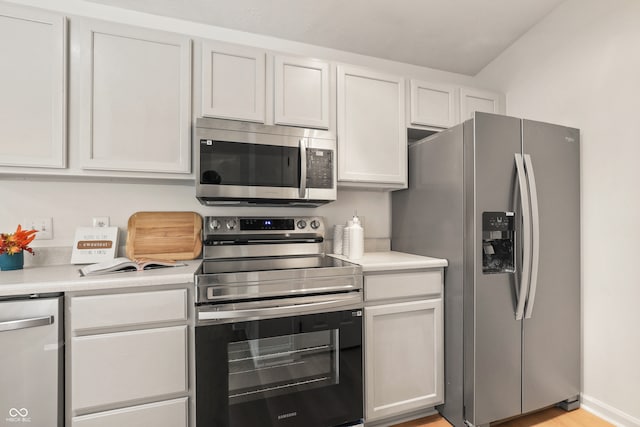 kitchen with white cabinets, light wood-type flooring, and appliances with stainless steel finishes