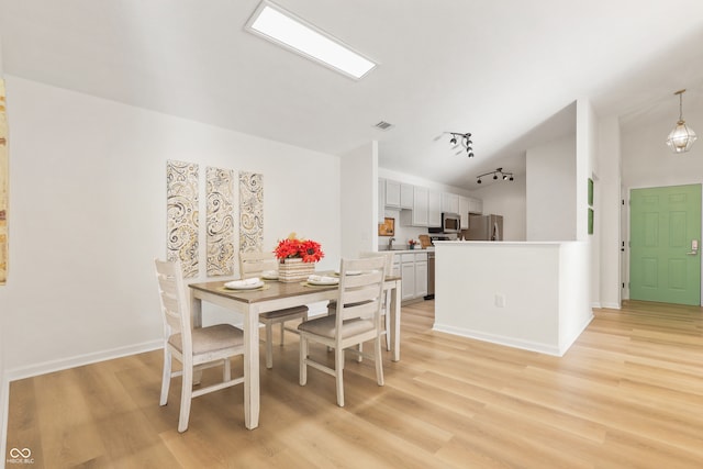 dining room featuring vaulted ceiling, track lighting, and light wood-type flooring