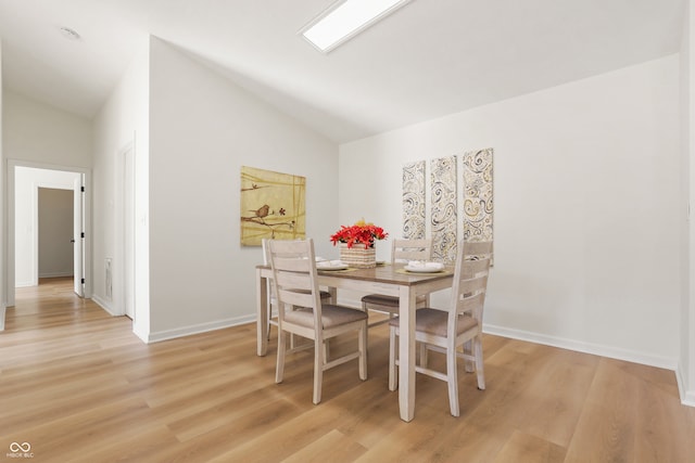 dining area with light hardwood / wood-style floors and vaulted ceiling