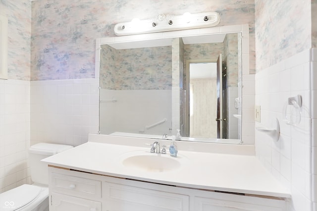 bathroom featuring vanity, toilet, and tile walls