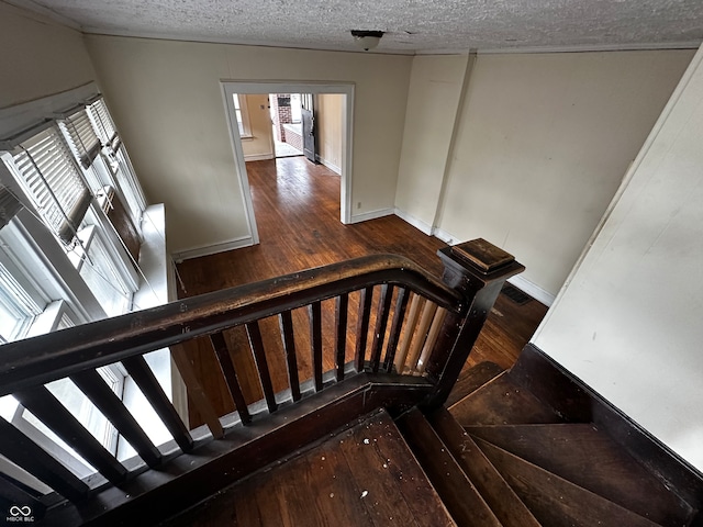 stairway with a textured ceiling and hardwood / wood-style flooring