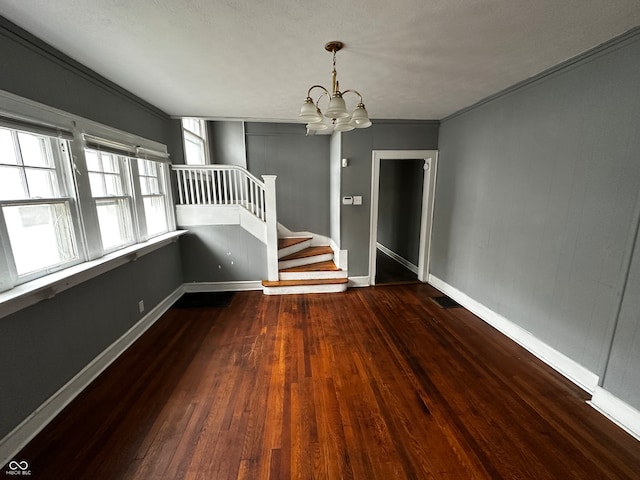 interior space featuring dark hardwood / wood-style flooring, ornamental molding, and an inviting chandelier