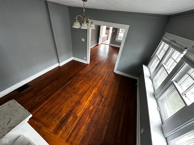 unfurnished dining area featuring dark hardwood / wood-style floors, crown molding, a textured ceiling, and a chandelier