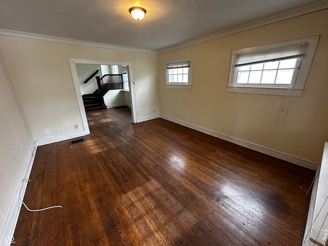 spare room featuring crown molding, a healthy amount of sunlight, and dark hardwood / wood-style floors