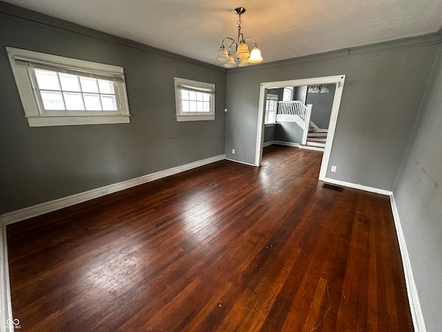 unfurnished dining area featuring crown molding, dark wood-type flooring, and an inviting chandelier