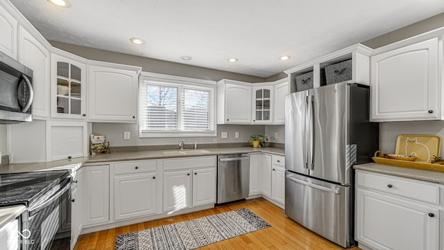 kitchen featuring appliances with stainless steel finishes, light hardwood / wood-style flooring, and white cabinetry