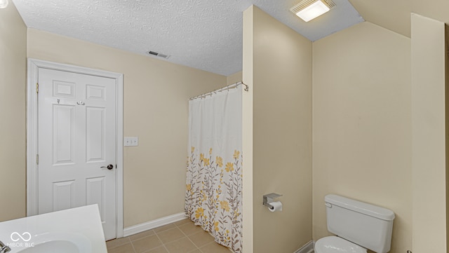 bathroom featuring a textured ceiling, vaulted ceiling, toilet, and a shower with curtain