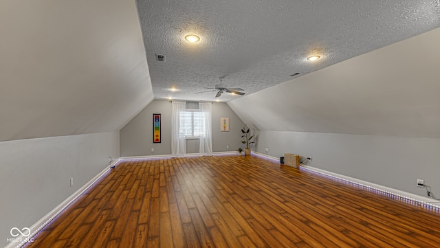 bonus room featuring hardwood / wood-style flooring, ceiling fan, lofted ceiling, and a textured ceiling