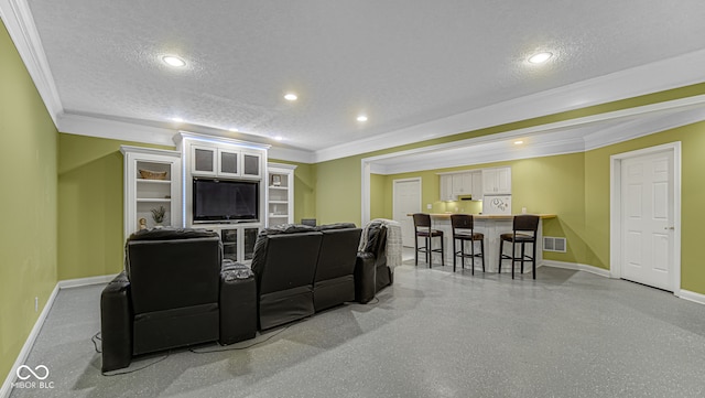 home theater room with a textured ceiling, recessed lighting, visible vents, baseboards, and ornamental molding