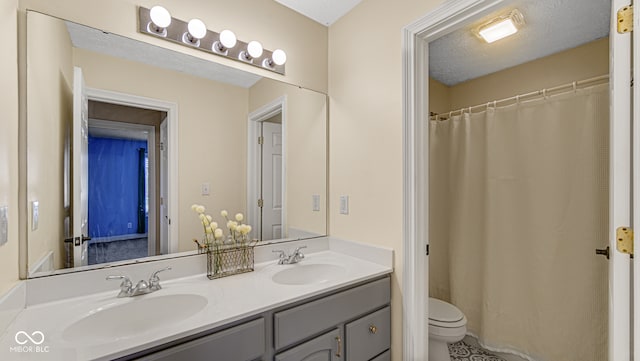 bathroom featuring vanity, a textured ceiling, and toilet