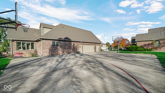 view of front of home featuring a shingled roof, brick siding, driveway, and a garage