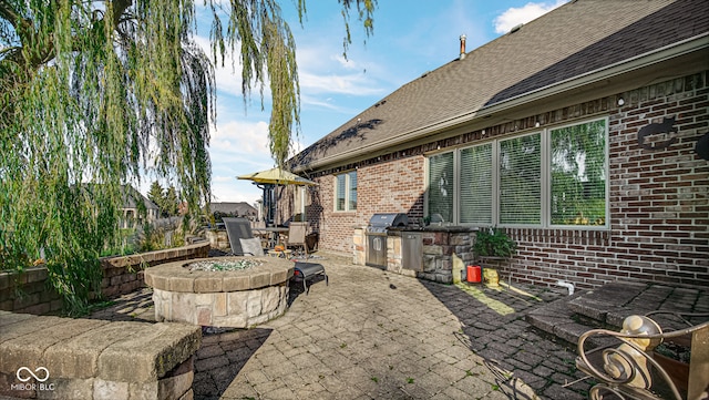 view of patio featuring a fire pit, outdoor dining area, and exterior kitchen