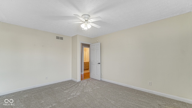 empty room featuring a textured ceiling, light colored carpet, and ceiling fan