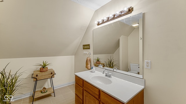 bathroom featuring vanity, toilet, and lofted ceiling