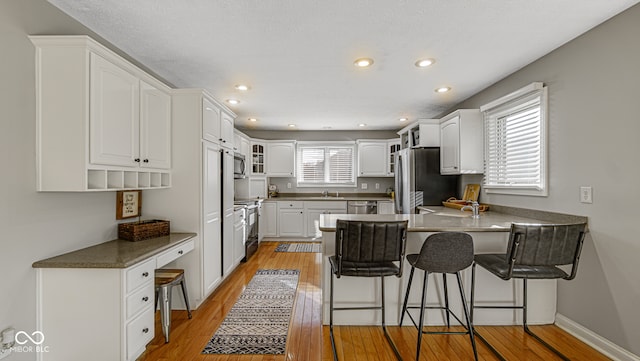 kitchen featuring white cabinets, plenty of natural light, a breakfast bar, and appliances with stainless steel finishes