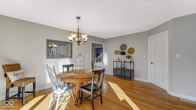 dining space with a notable chandelier, visible vents, baseboards, stairs, and light wood-style floors