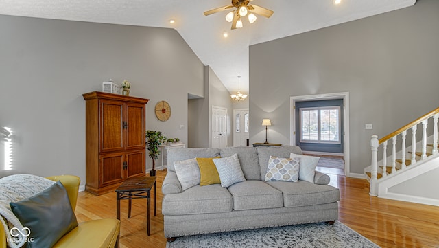 living room with a textured ceiling, high vaulted ceiling, light hardwood / wood-style floors, and ceiling fan with notable chandelier