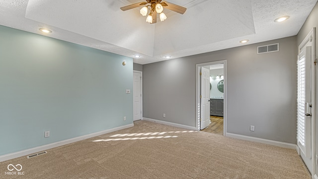 empty room with baseboards, visible vents, vaulted ceiling, and light colored carpet