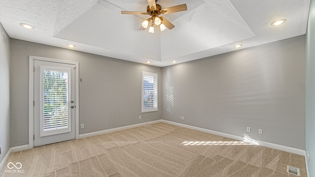 unfurnished room with ceiling fan, light colored carpet, a textured ceiling, and a wealth of natural light