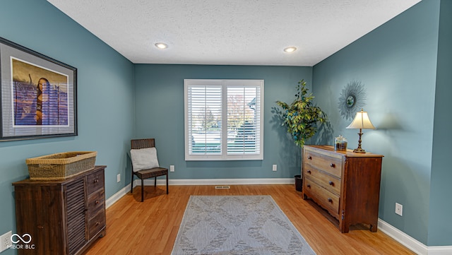 sitting room featuring light hardwood / wood-style floors and a textured ceiling