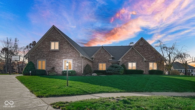 view of front of home featuring brick siding and a lawn