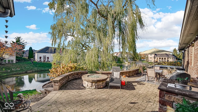 view of patio with an outdoor kitchen, a water view, and an outdoor fire pit