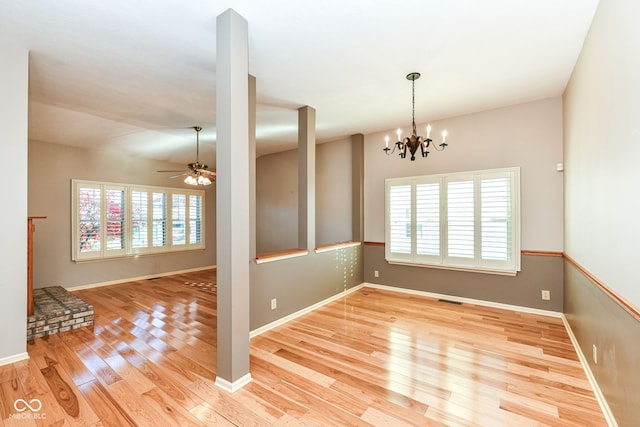 unfurnished room with ceiling fan with notable chandelier and light wood-type flooring