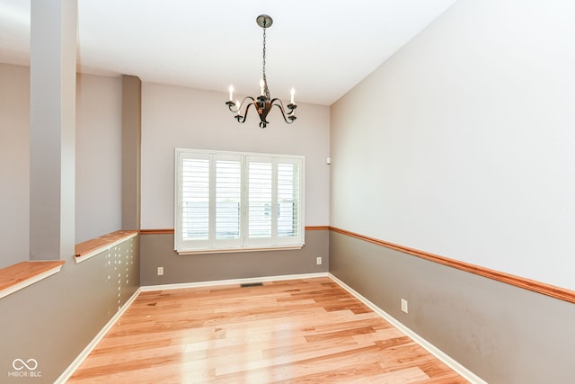 empty room featuring light hardwood / wood-style floors and a notable chandelier