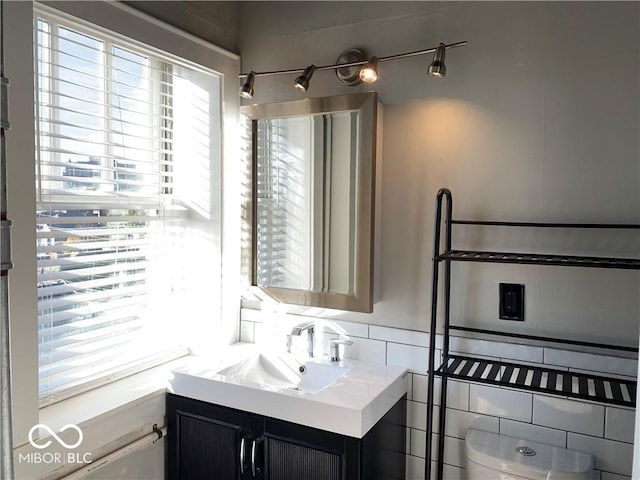 bathroom with tasteful backsplash, vanity, and toilet